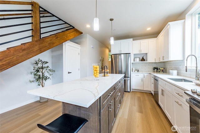kitchen with a sink, open shelves, stainless steel appliances, light wood-style floors, and a kitchen island
