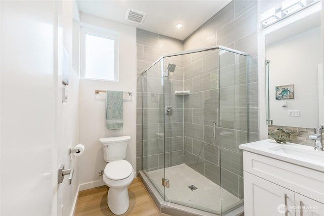bathroom featuring vanity, toilet, visible vents, and a shower stall