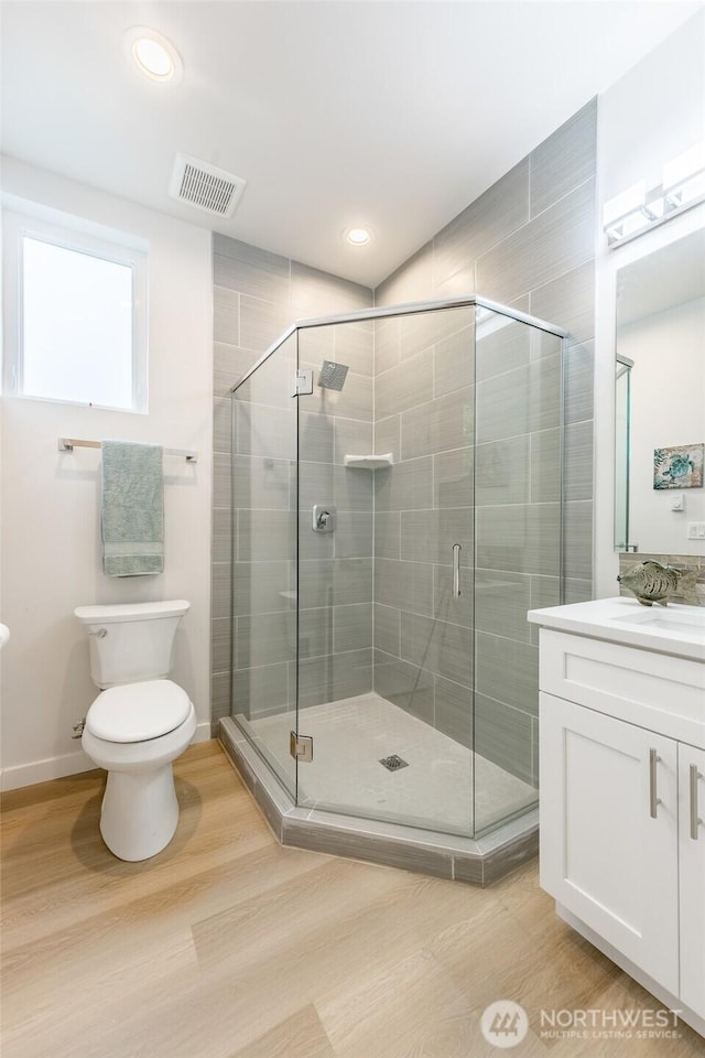 full bath with a stall shower, toilet, visible vents, and wood finished floors