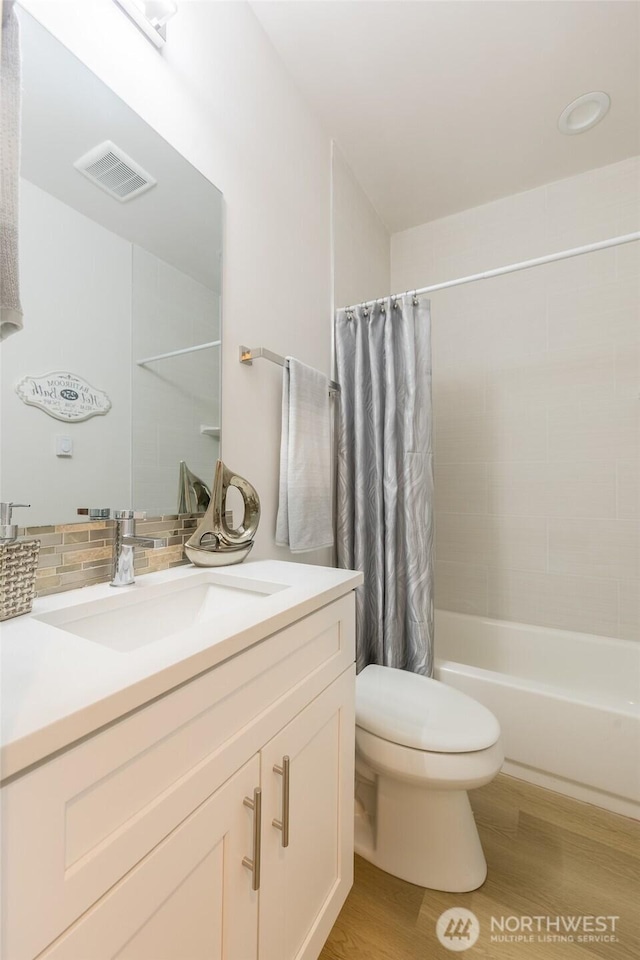 bathroom with toilet, shower / bath combo with shower curtain, wood finished floors, vanity, and visible vents
