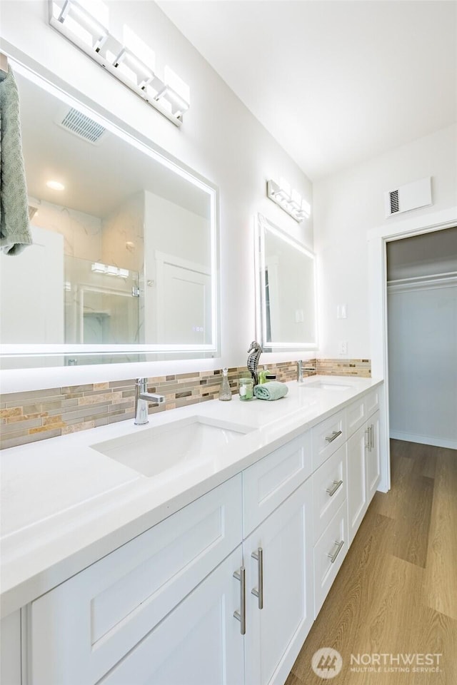 bathroom featuring double vanity, tasteful backsplash, a stall shower, and a sink