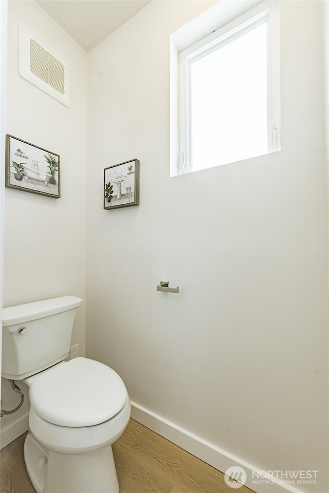 bathroom with toilet, baseboards, visible vents, and wood finished floors