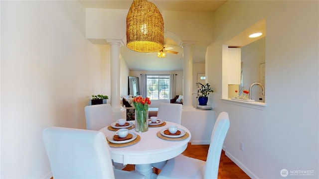 dining space with baseboards, wood finished floors, and decorative columns