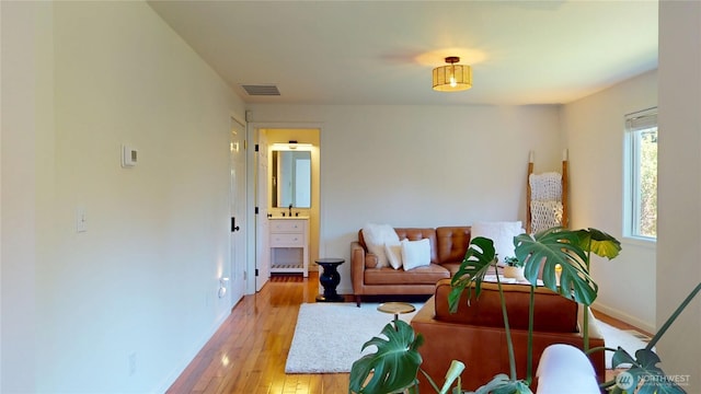 living area featuring light wood-type flooring, visible vents, and baseboards