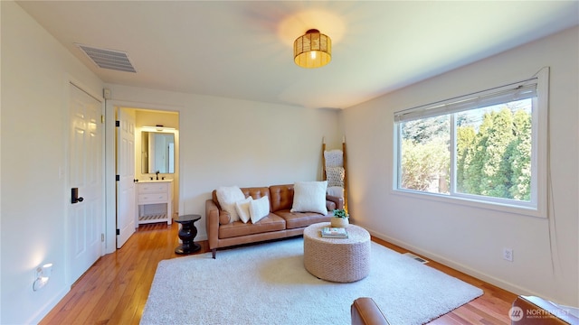 living room with baseboards, light wood finished floors, and visible vents