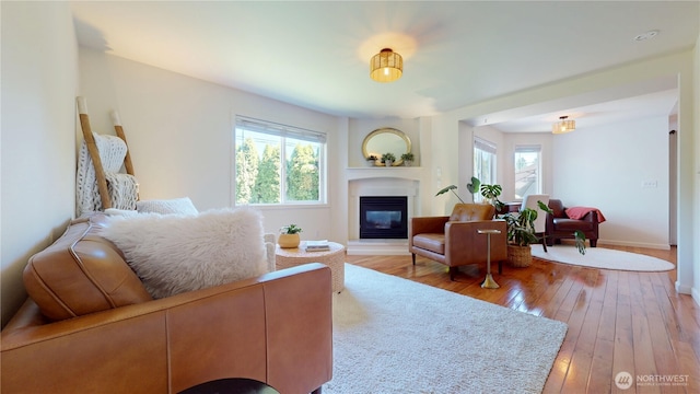 living room featuring baseboards, a glass covered fireplace, and hardwood / wood-style flooring