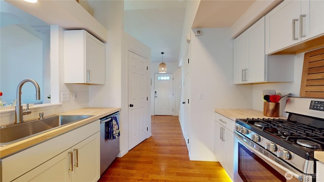 kitchen featuring appliances with stainless steel finishes, a sink, light wood-type flooring, and light countertops