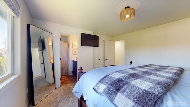 bedroom with connected bathroom and light colored carpet