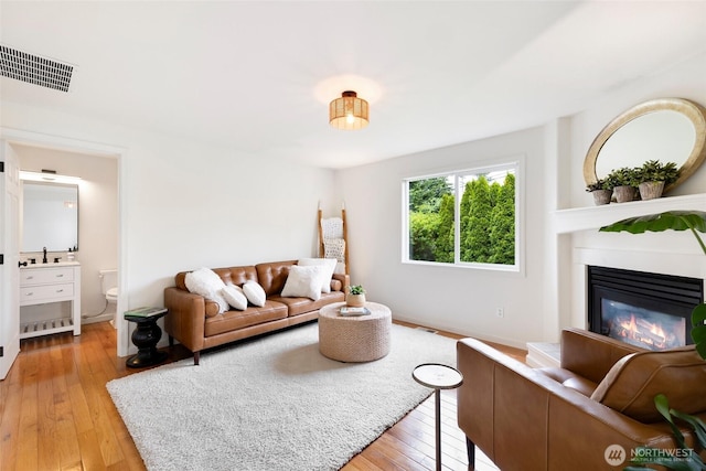 3416 189th St SE, Bothell, WA 98012 - living area featuring light wood-type flooring, a glass covered fireplace, and baseboards
