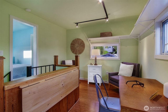 bedroom with wood finished floors, rail lighting, and baseboards