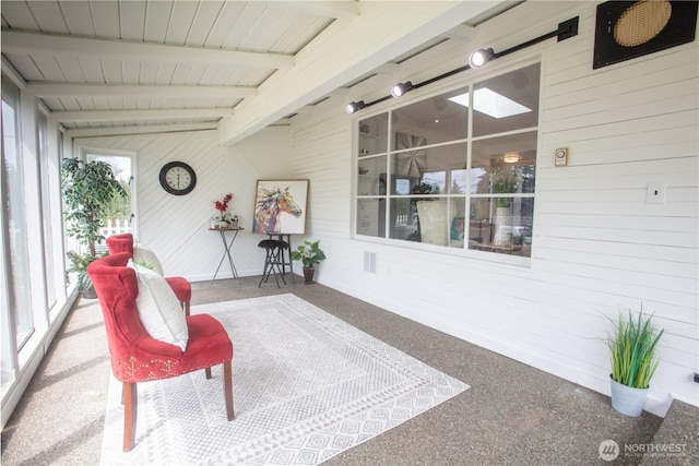 sunroom featuring wooden walls, beamed ceiling, and carpet