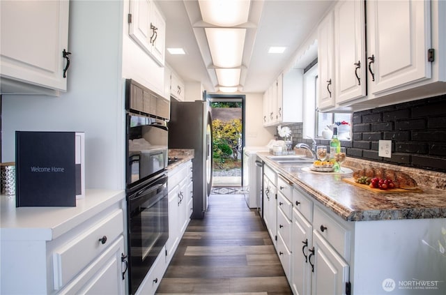kitchen featuring a sink, decorative backsplash, dark wood-style flooring, white cabinets, and stainless steel appliances