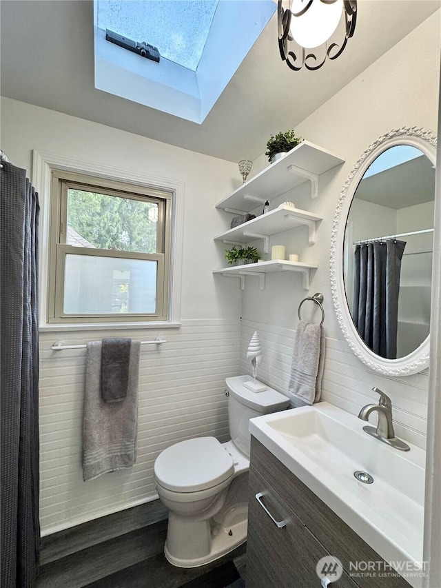 full bath with a skylight, tile walls, toilet, vanity, and decorative backsplash