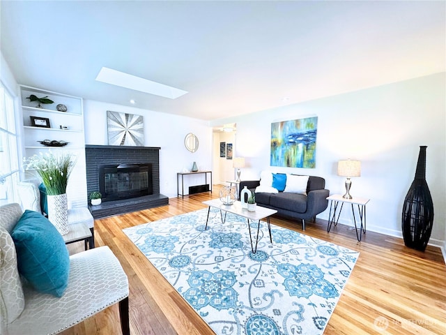 living area with a skylight, a fireplace, and wood finished floors