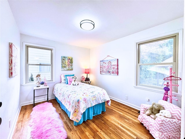 bedroom featuring multiple windows, wood finished floors, and baseboards