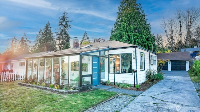view of front of property featuring a sunroom, an outbuilding, a detached garage, and a chimney