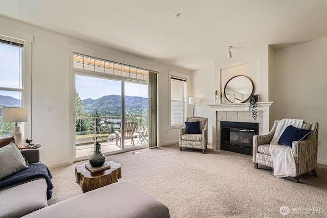 living room with a mountain view, carpet, a tile fireplace, and plenty of natural light