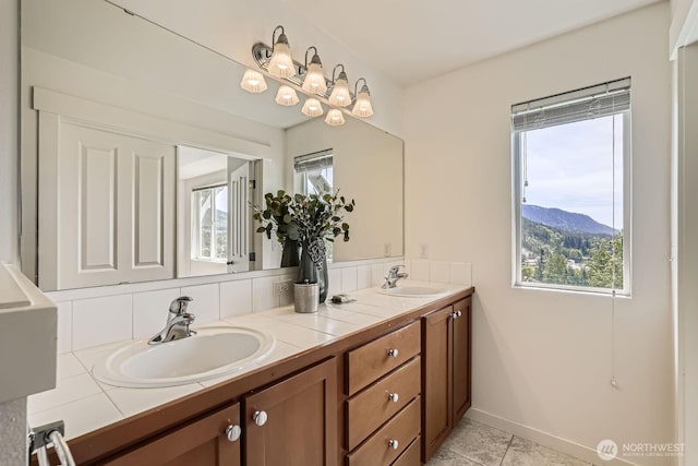 full bath with double vanity, tile patterned flooring, a mountain view, and baseboards