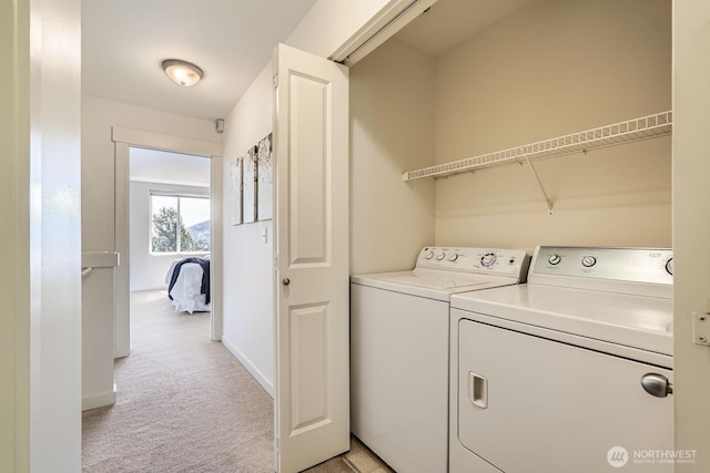 clothes washing area featuring light carpet, washer and clothes dryer, and baseboards