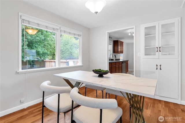 dining space with baseboards and light wood-style flooring
