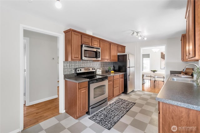 kitchen featuring appliances with stainless steel finishes, a sink, light floors, and tasteful backsplash