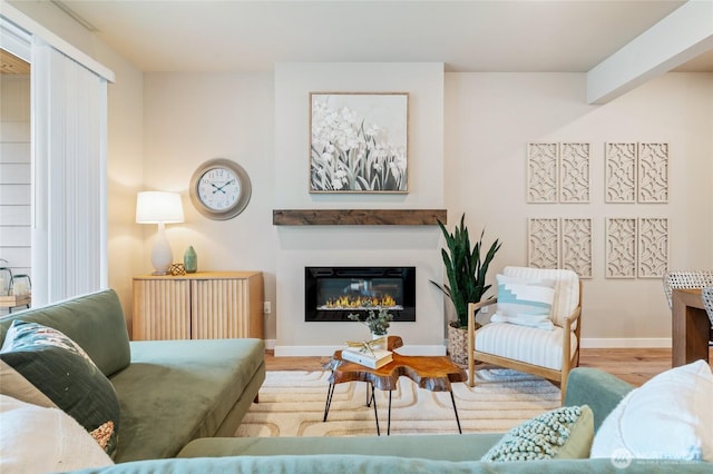 living room featuring baseboards, a glass covered fireplace, and wood finished floors
