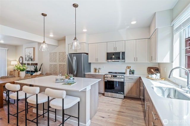 kitchen with a breakfast bar area, a center island, a sink, stainless steel appliances, and backsplash