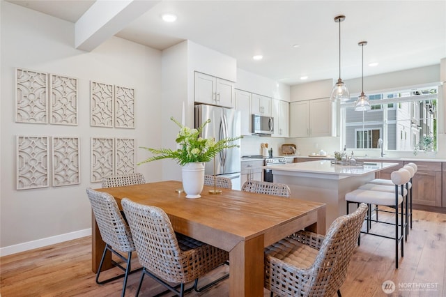 dining area with light wood-style flooring, baseboards, and recessed lighting
