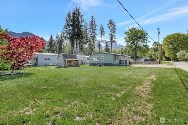 view of yard with a storage shed, a mountain view, and an outbuilding