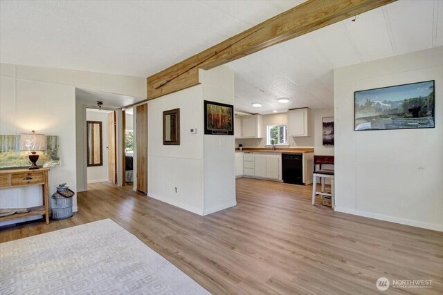 living area featuring baseboards, vaulted ceiling with beams, and light wood-style floors