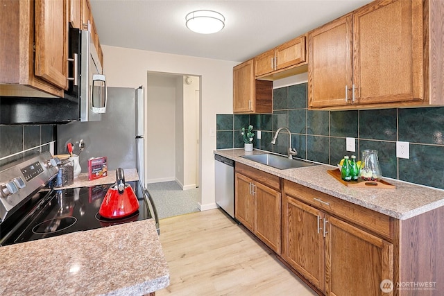kitchen with appliances with stainless steel finishes, a sink, light countertops, and tasteful backsplash