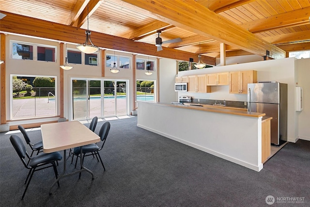 kitchen featuring stainless steel appliances, dark colored carpet, wood ceiling, plenty of natural light, and beamed ceiling
