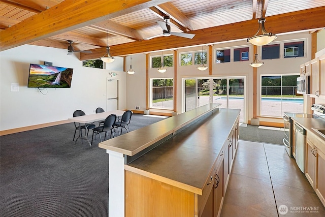 kitchen with stainless steel countertops, wooden ceiling, a ceiling fan, stainless steel microwave, and beamed ceiling