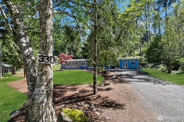 view of front of property with driveway, an outdoor structure, and a front lawn