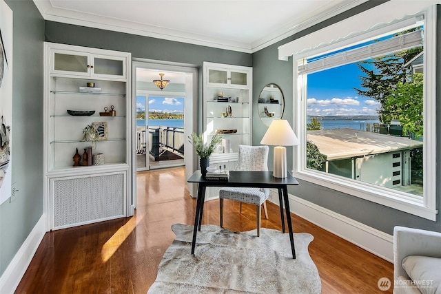 home office featuring ornamental molding, a water view, baseboards, and wood finished floors