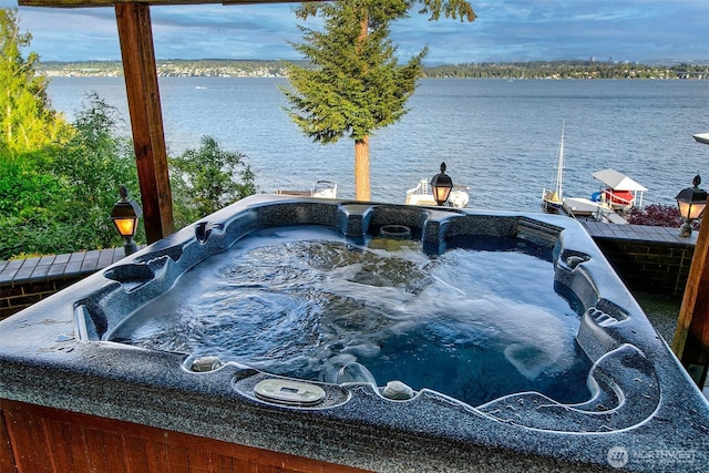 exterior space with a hot tub and a water view