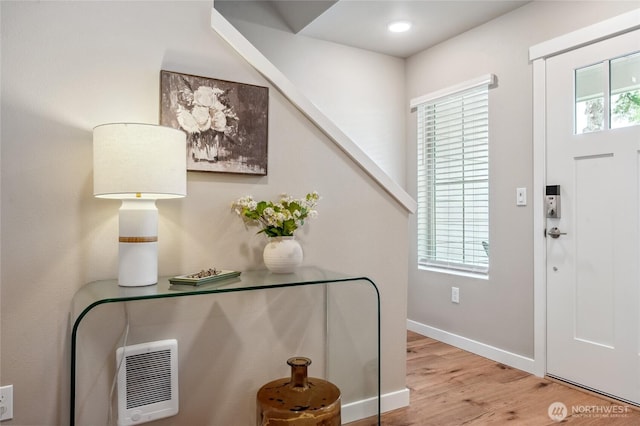 foyer entrance featuring baseboards, heating unit, and wood finished floors