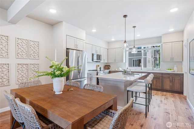dining space with baseboards, light wood-type flooring, and recessed lighting