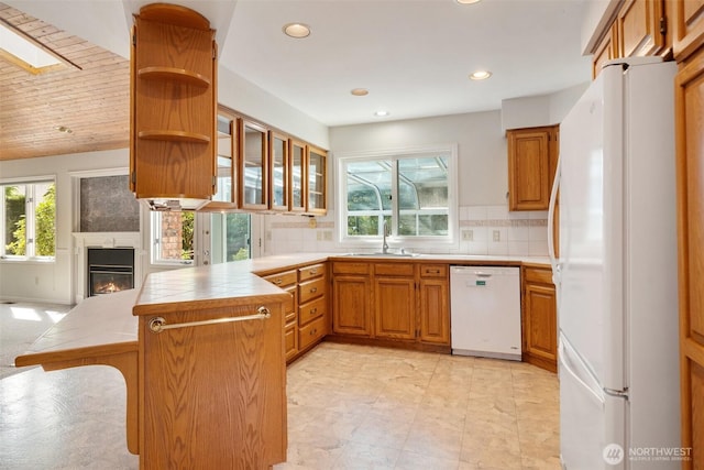 kitchen featuring white appliances, plenty of natural light, a peninsula, and a sink