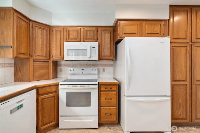 kitchen featuring backsplash, brown cabinets, white appliances, and tile countertops