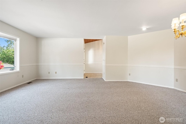 carpeted spare room featuring baseboards and an inviting chandelier