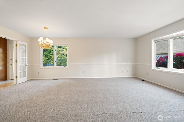 spare room featuring french doors, light colored carpet, visible vents, an inviting chandelier, and baseboards