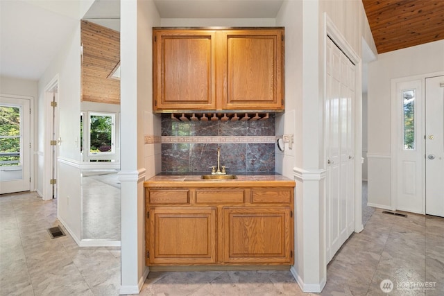 bar with wood ceiling, a sink, visible vents, backsplash, and wet bar