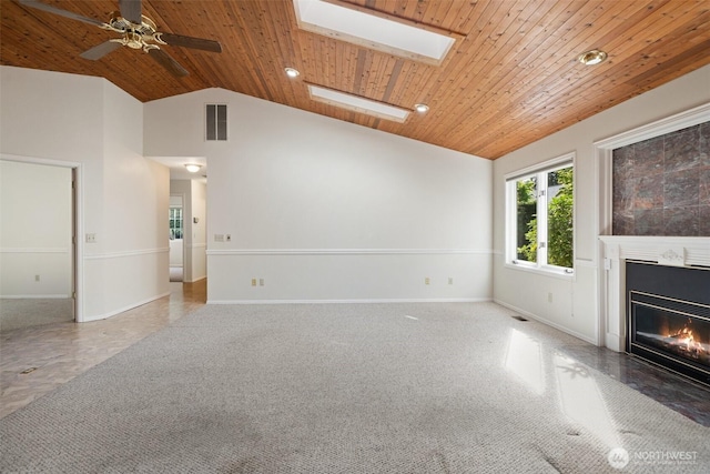 unfurnished living room featuring wood ceiling, visible vents, lofted ceiling with skylight, and a fireplace with flush hearth