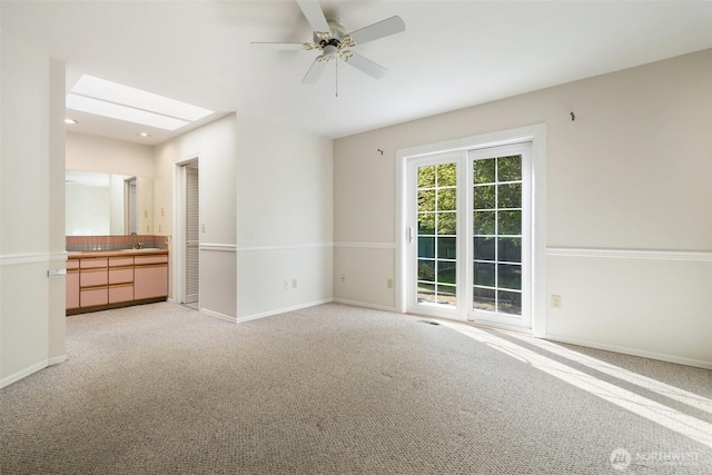 spare room featuring a sink, light colored carpet, baseboards, and a ceiling fan