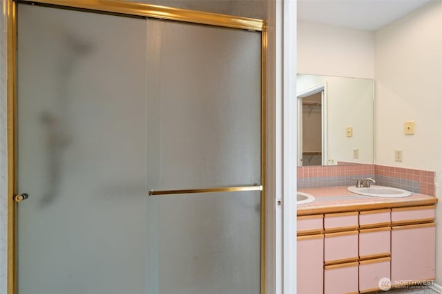 full bathroom with double vanity, decorative backsplash, a stall shower, and a sink