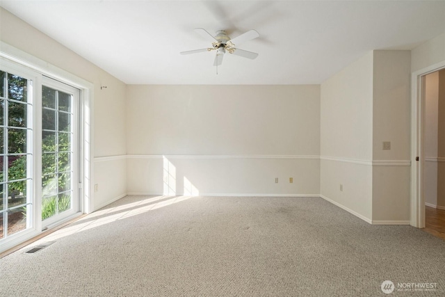 carpeted empty room featuring baseboards, a wealth of natural light, ceiling fan, and visible vents