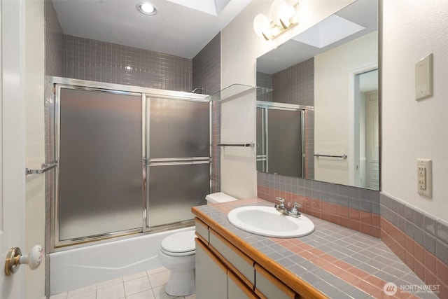 bathroom with toilet, tile patterned flooring, bath / shower combo with glass door, vanity, and recessed lighting