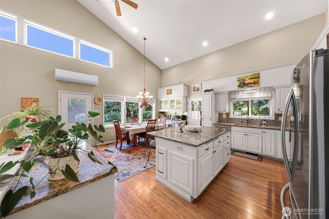 6874 Golf View Dr, Lynden, WA 98264 - kitchen with freestanding refrigerator, a wall unit AC, high vaulted ceiling, white cabinetry, and light wood-type flooring