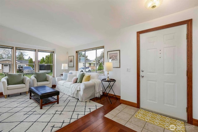 living room with baseboards, vaulted ceiling, and light wood-style floors